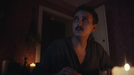 a man contemplating in a candlelit room