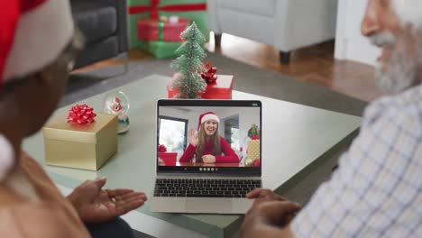 Happy-senior-african-american-couple-on-video-call-with-female-friend-at-christmas-time