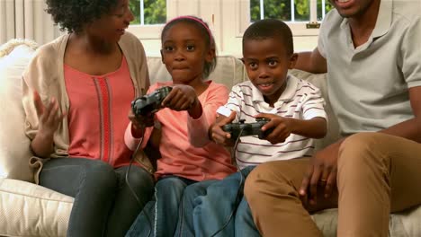 smiling family on sofa with kids playing video games