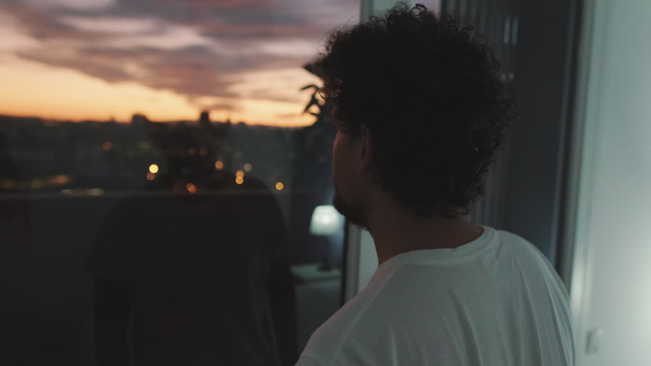 Man looking out window at sunset