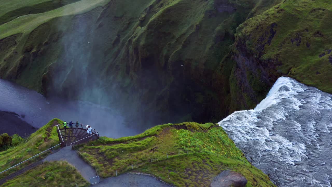 turistas en la plataforma de observación admirando el impresionante paisaje de la cascada skogafoss en skogar, islandia