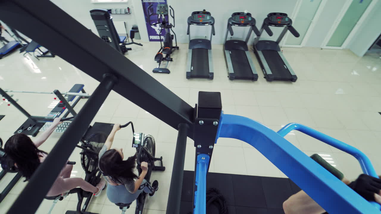 Healthy female bodybuilder doing tightening on a crossbar on the gym background. Modern sports center and women training on simulators.