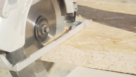 handheld close up shot of cutting oriented strand board with circular wood saw