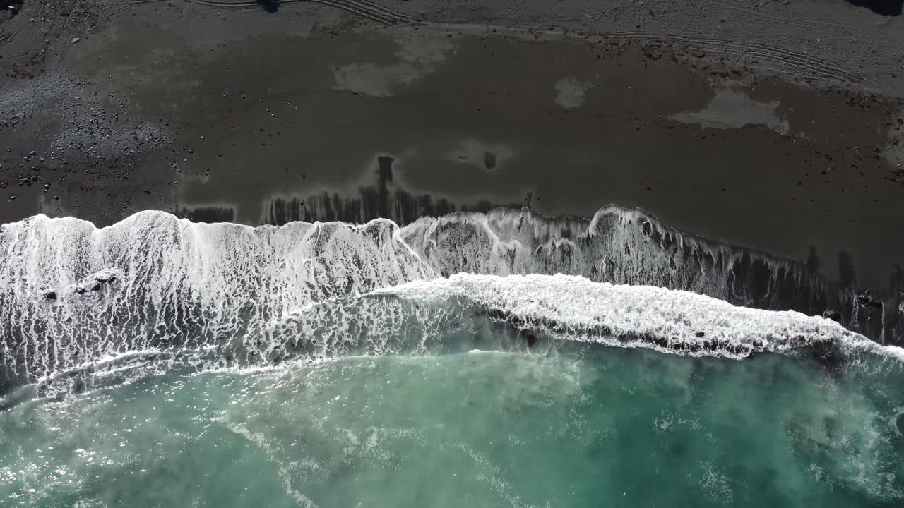 회색 모래가 있는 해변에 부서지는 파도의 조감도