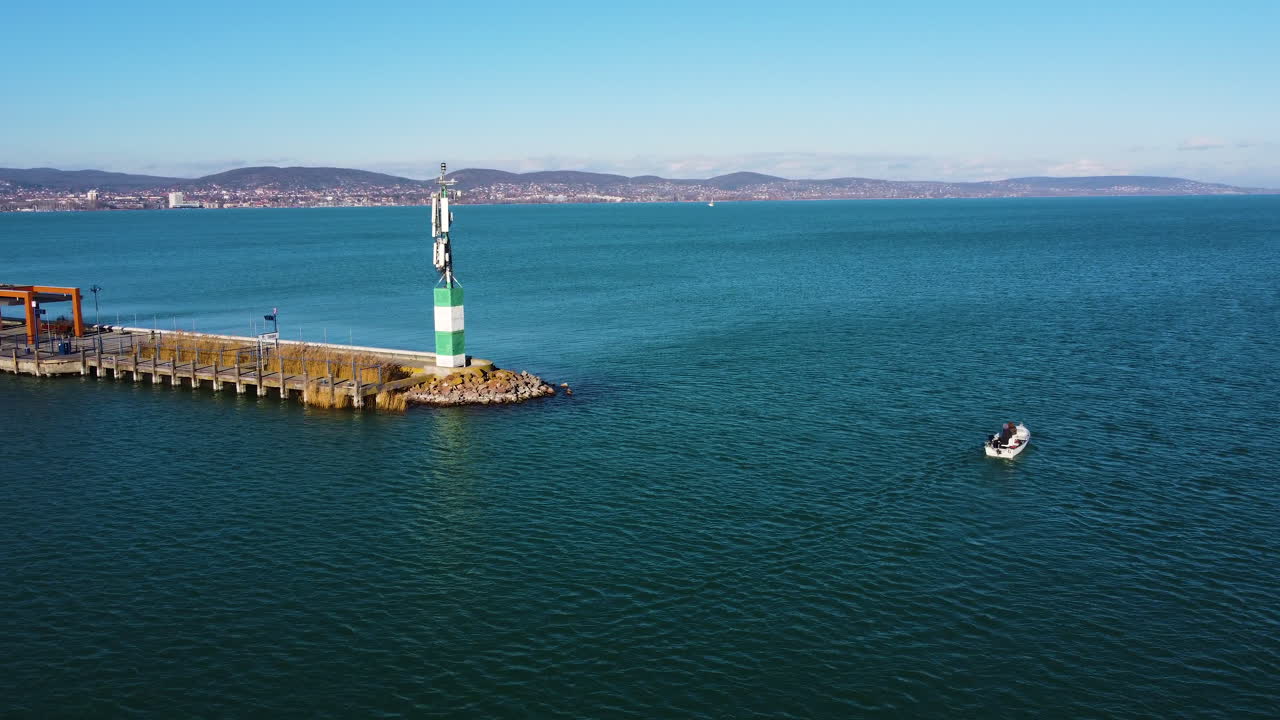 Wide aerial of distant coastline at Hajokikoto, Lake Balaton with soft waves and blue horizon