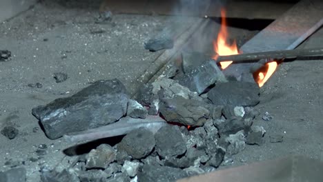 blacksmith in a fire heats metal to forge a product