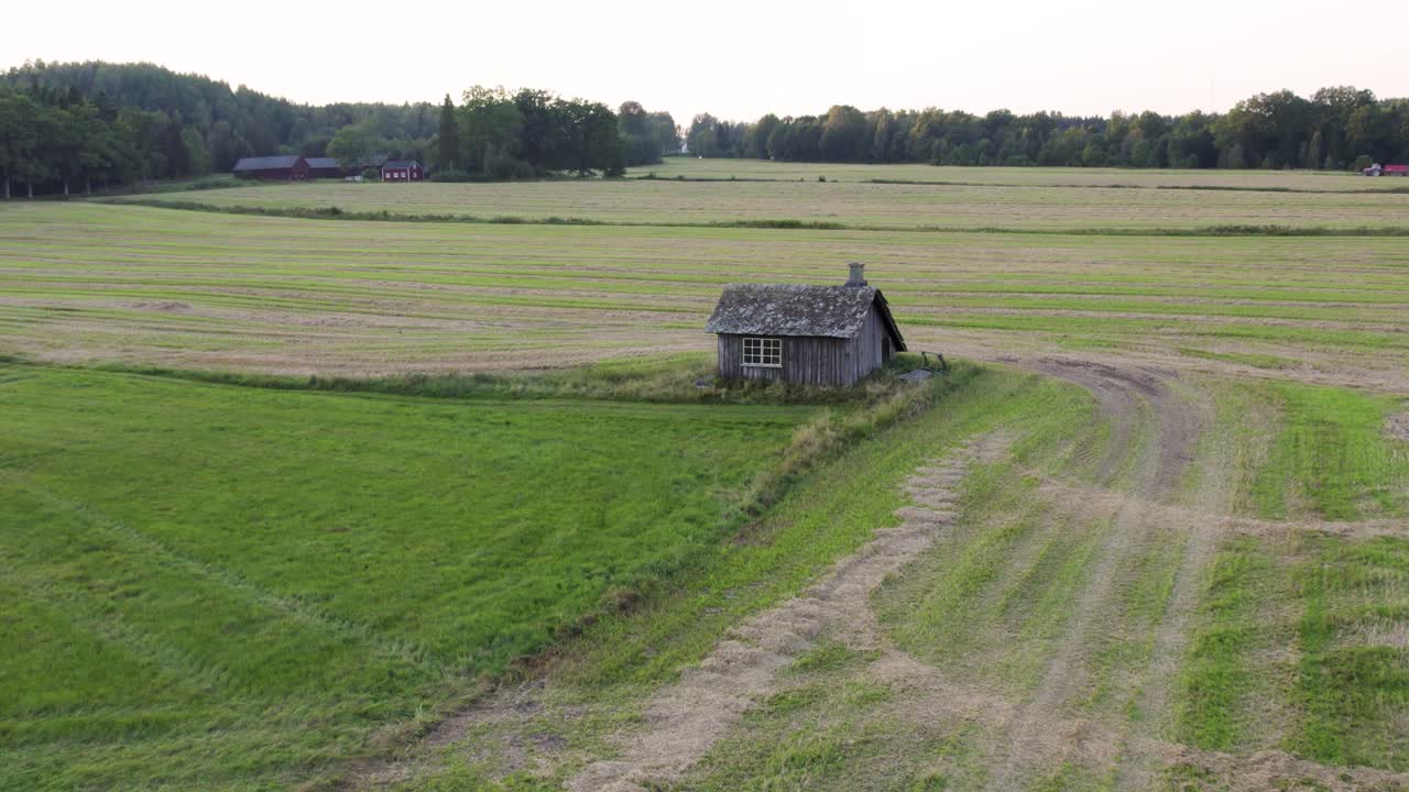 Push in drone shot of old blacksmith workshop in a green field during the day in Sweden
