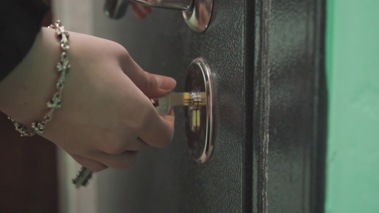 Hand turns key and opens door, lock releases with subtle click and handle movement, interior corridor revealed with warm light and relieved arrival, gentle step across threshold signaling return