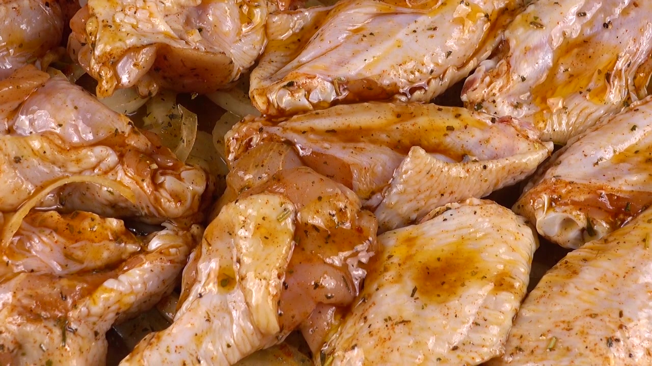 Le ali di pollo marinate sono disposte sugli anelli di cipolla in una pirofila di vetro