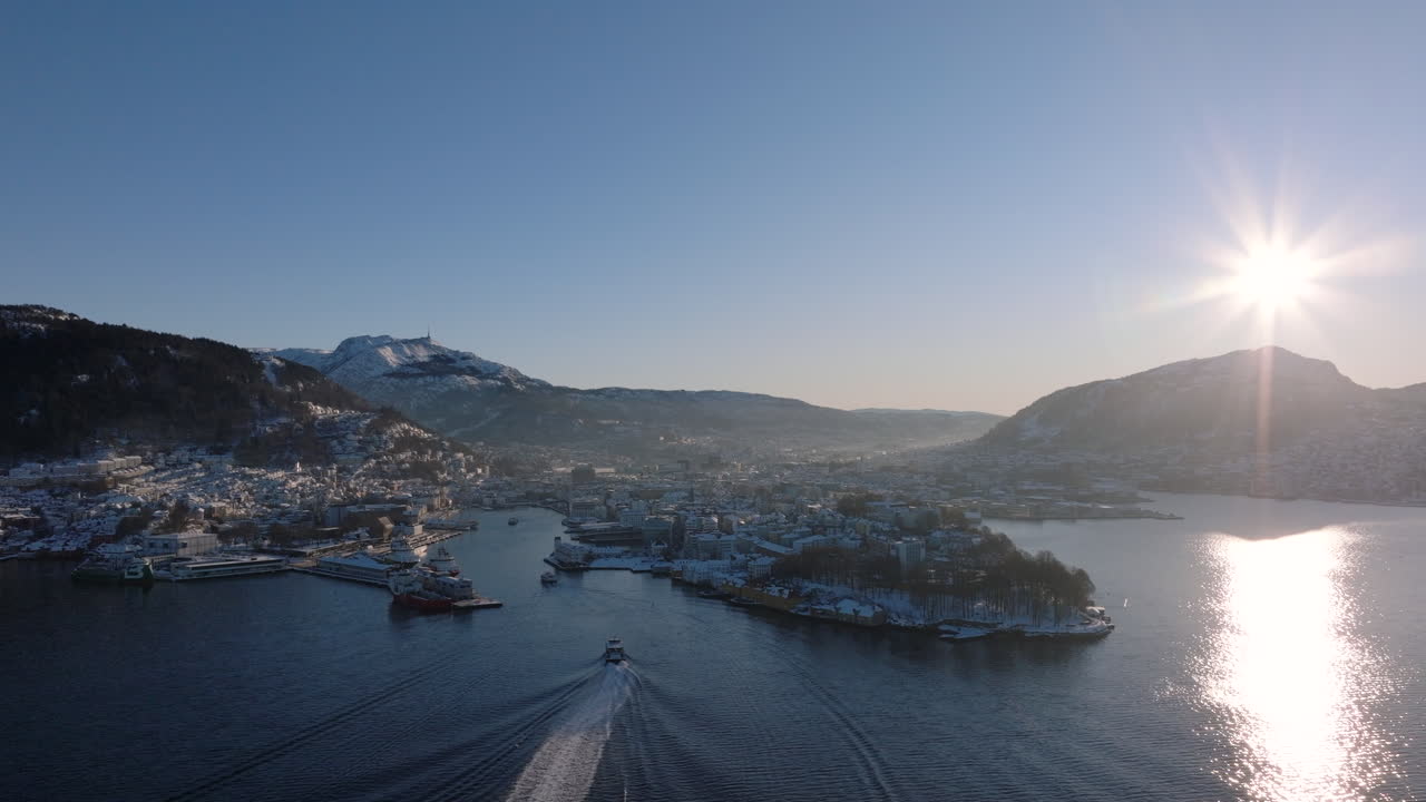 Aerial shot of Bergen and the surrounding mountains covered in snow on a sunny winter day