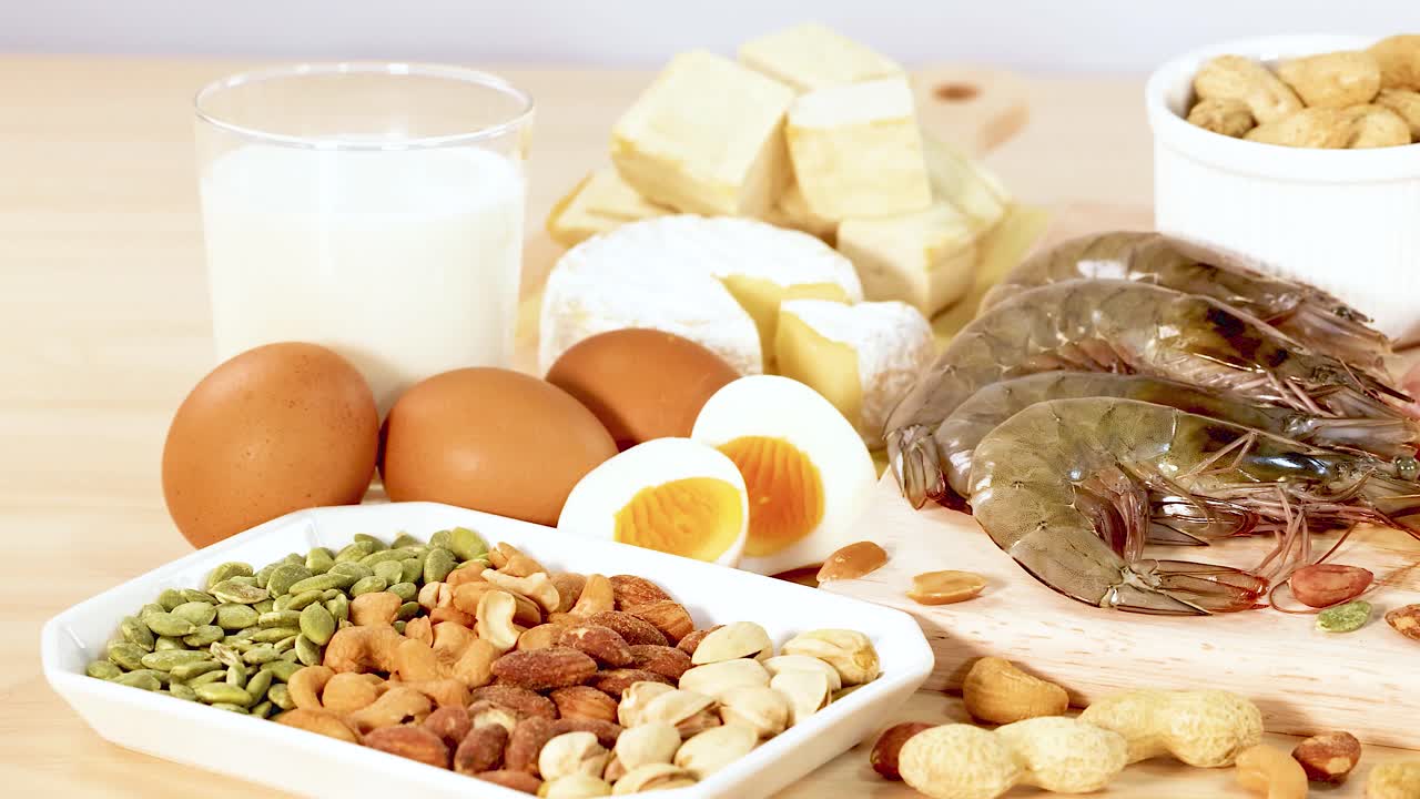 유제품, 견과류, 고기 등 단백질이 풍부한 다양한 음식들이 나무 표면에 예술적으로 배열되어 있습니다.