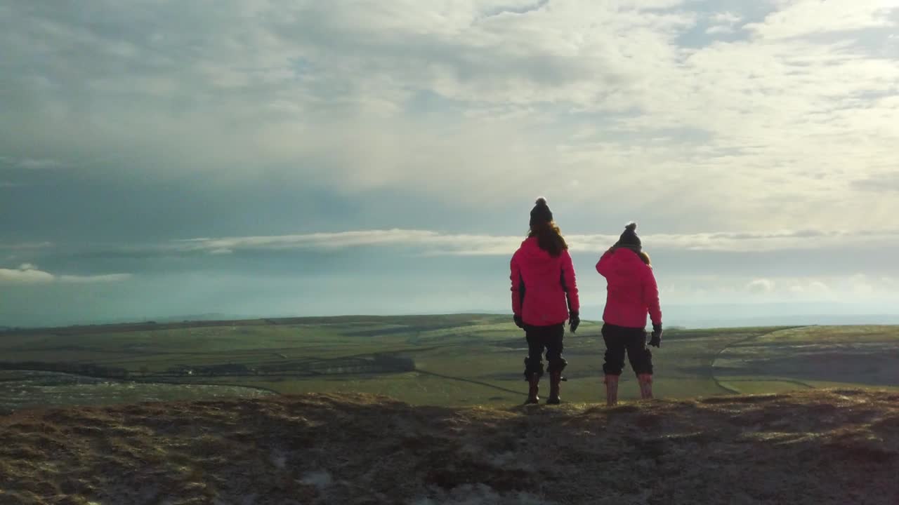 Kids reaching summit of sunny mountain top slomo during snow shower