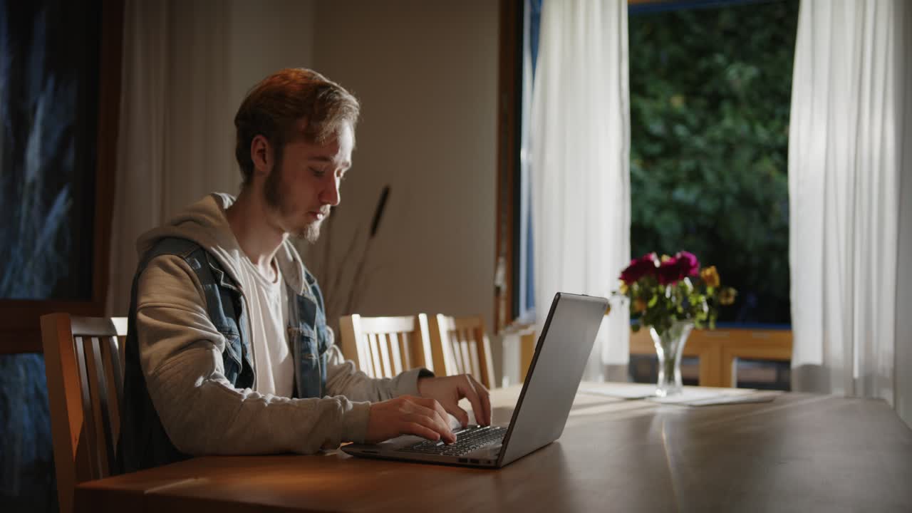 someone is typing on the laptop in the living room at night, with light from outside