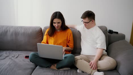 una chica sentada con una computadora portátil - buenas noticias o éxito celebrando con su amiga con síndrome de down