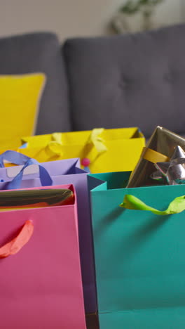vídeo vertical de regalos envueltos en bolsas de colores con etiqueta en la mesa en el salón de la casa 1