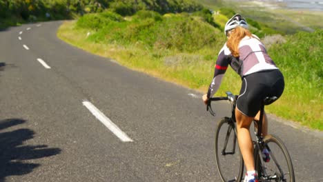 Ciclista-Femenina-En-Bicicleta-Por-Una-Carretera-Rural-4k