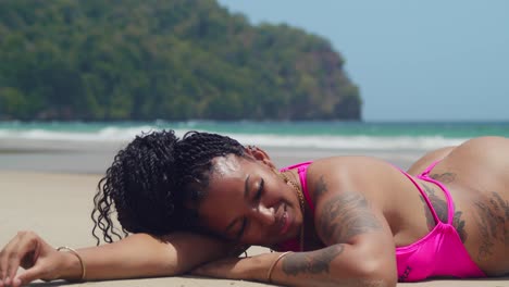Enjoying a perfect day, a girl in a pink bikini relaxes at Las Cuevas Beach on the Caribbean island of Trinidad.