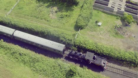 vista aérea de una locomotora de vapor tirando de vagones a través de un paso a nivel en la estación de tren de bodiam, east sussex, inglaterra