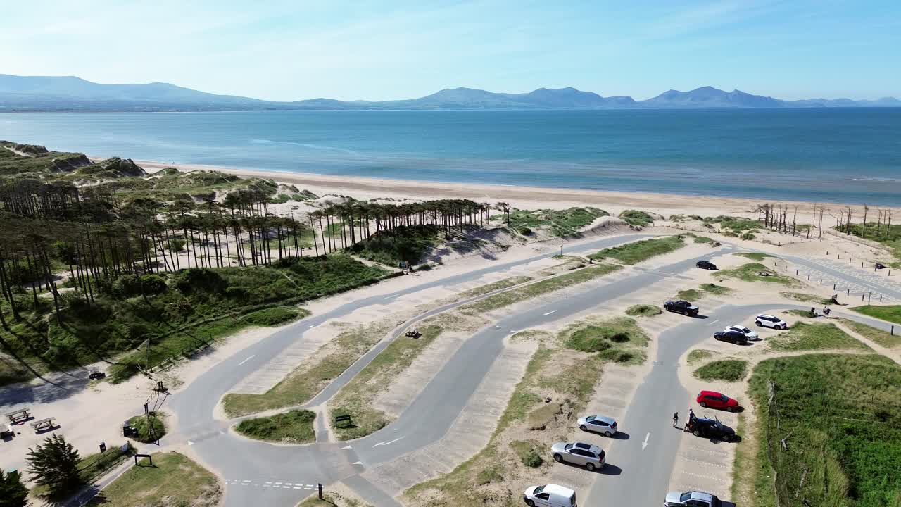 Newborough beach aerial view across sunny woodland car park coastline and Snowdonia mountain range