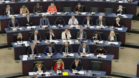 large group of people sitting at desks in a formal setting