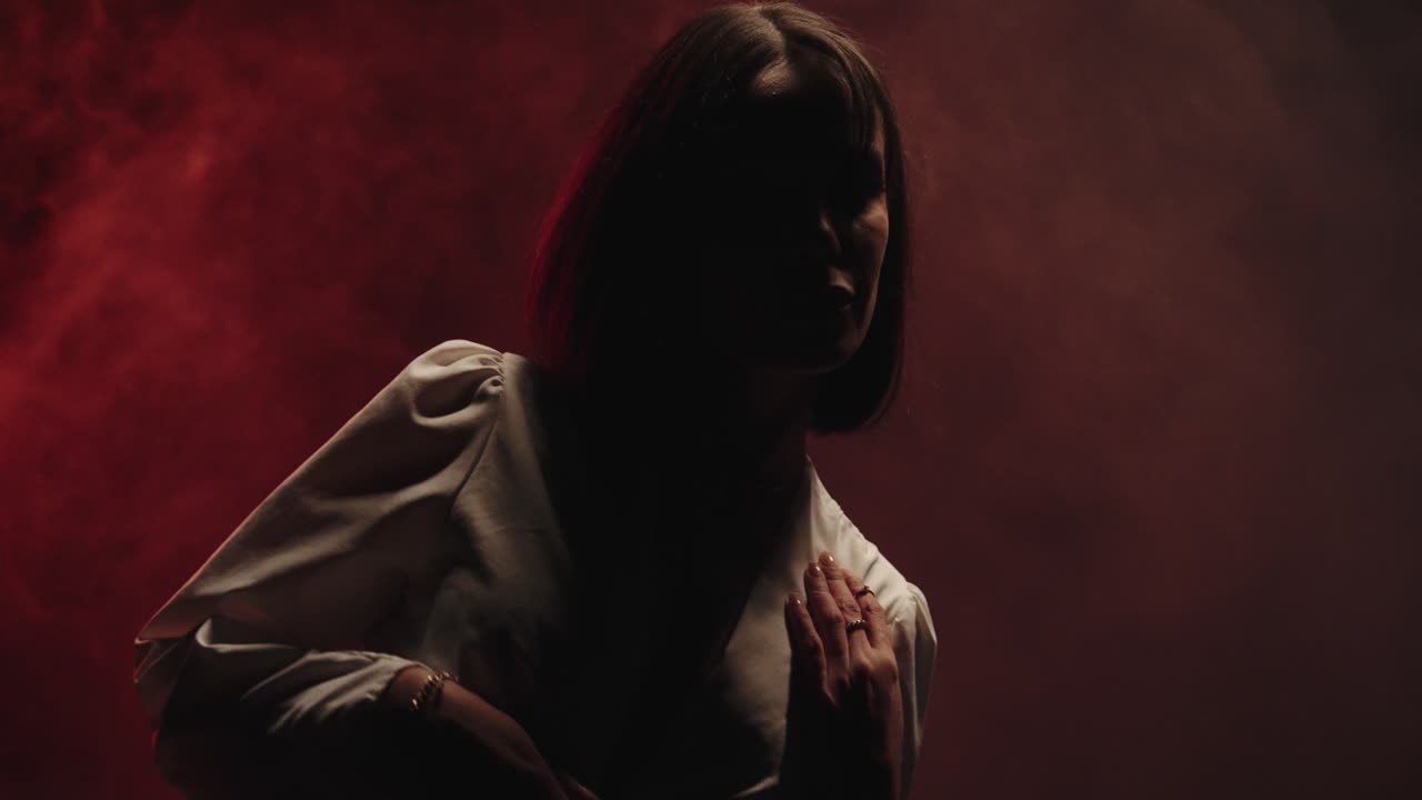 Mysterious woman in the dark with fog. she is dancing in slow motion