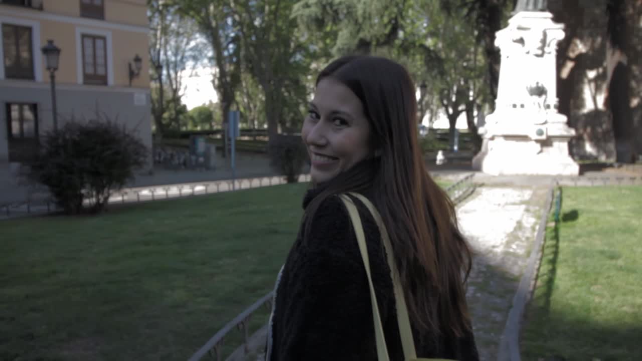 una joven latina caminando, girando y sonriendo en madrid.