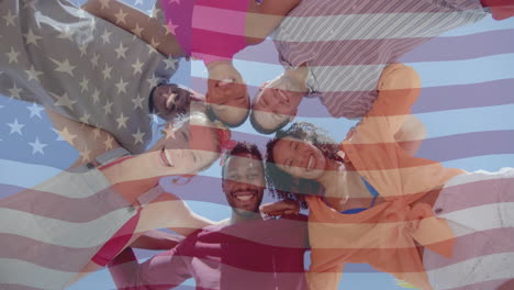 animation of american flag over below view of happy diverse friends embracing in the sun