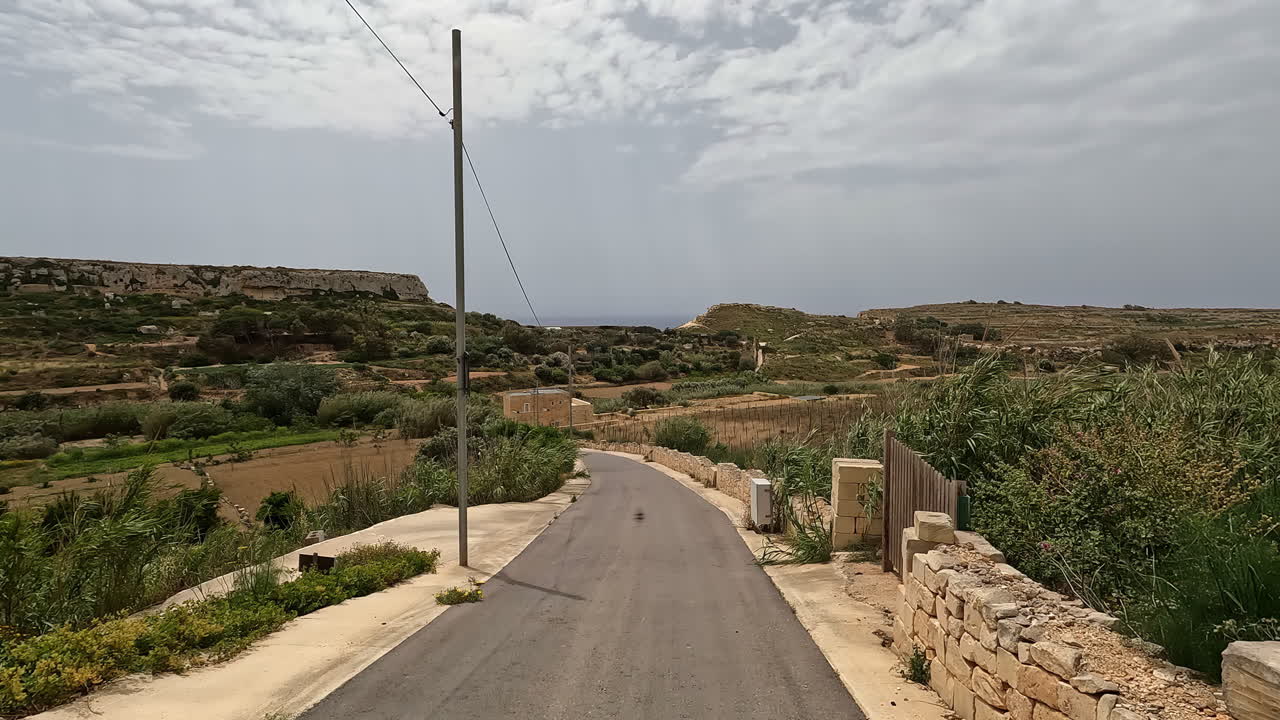 dolly a lo largo de un camino vacío con pared de roca, valla de madera y plantas tropicales