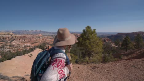 tracking shot, young woman hiking on stunning canyon trail in western usa.