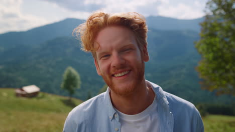 portrait happy man smiling on green meadow. red hair guy relaxing on vacation.