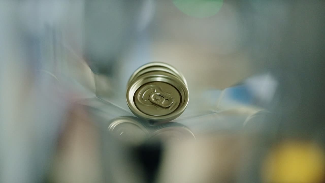 Golden can tops moving along a shaft to join a production line for canning beverages