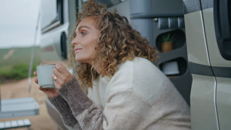 relaxed traveller drinking coffee sitting trailer stairs close up. happy woman