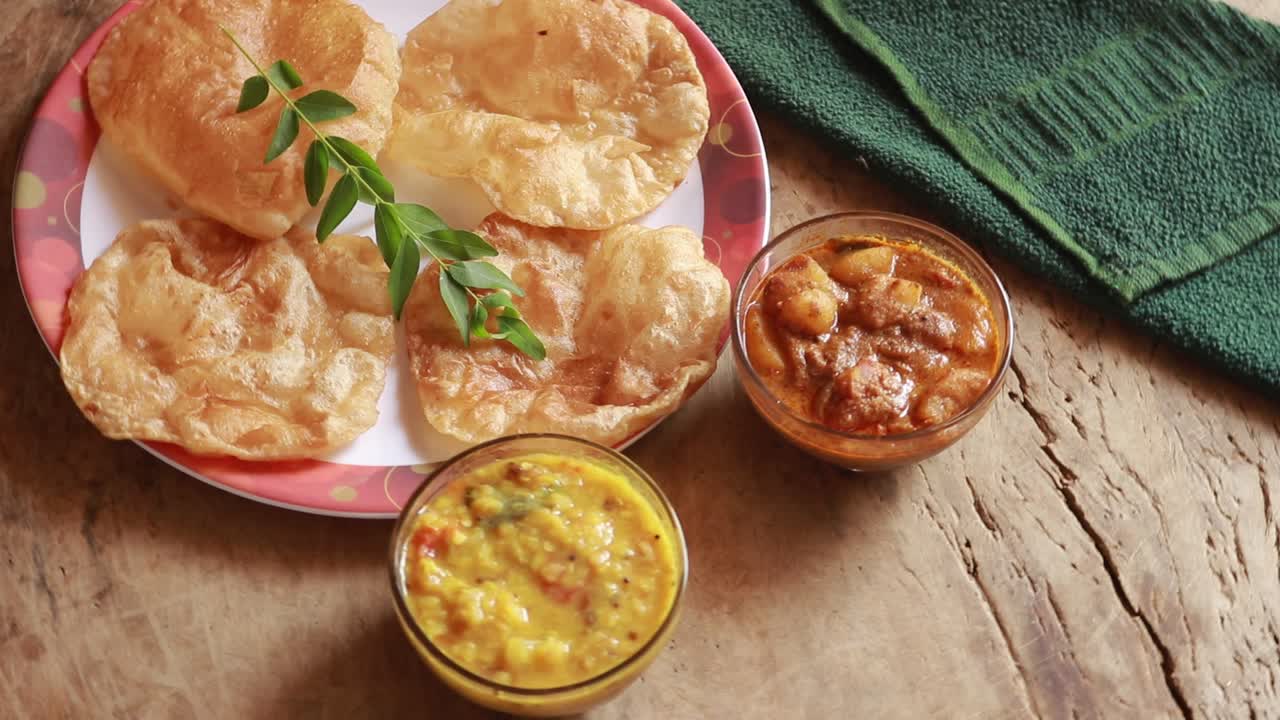 rotación chole bhature o curry de garbanzos y puri frito servido en vajilla de terracota sobre fondo de madera