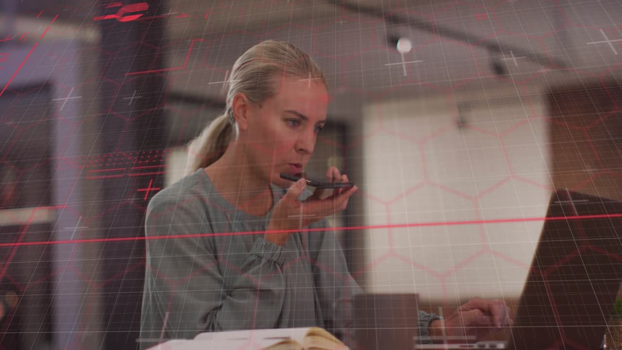 Reaching for smartphone and dictating message, woman alternating typing business notes on laptop