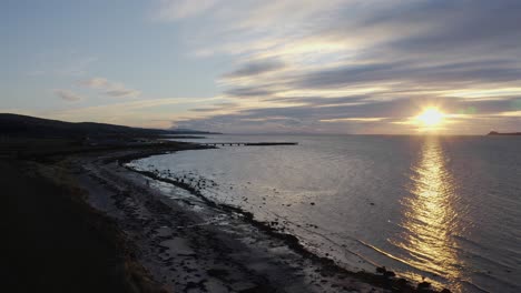 aerial - shipwreck on a beach at sunset, kintyre, scotland, wide forward shot