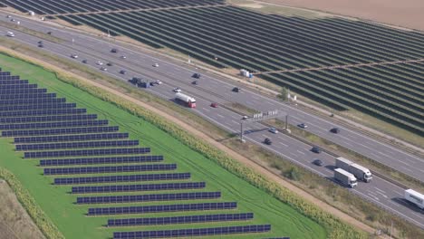 highway cuts through two large solar parks, one with east-west vertical panels, germany, high angle drone view