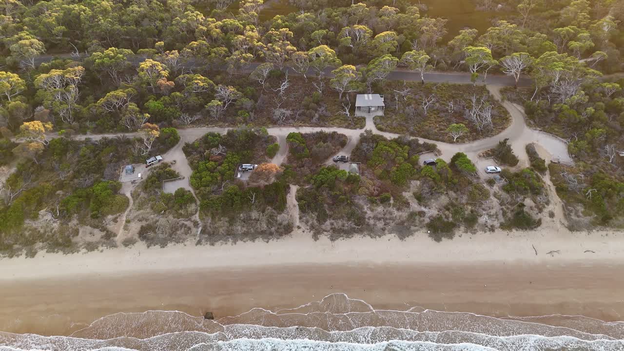 Campground seafront at sunset, Coles Bay in Tasmania, Australia. Aerial top-down backward