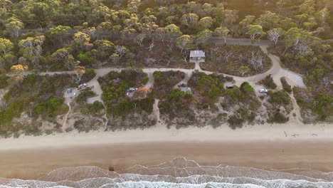 campground seafront at sunset, coles bay in tasmania, australia. aerial top-down backward