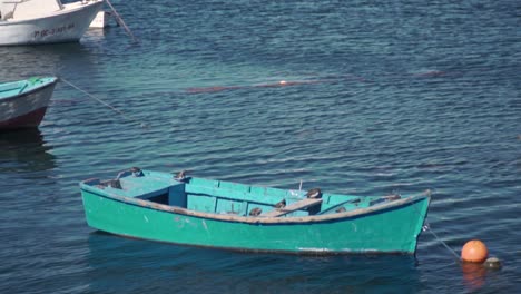 small teal fishing boat in a calm harbor