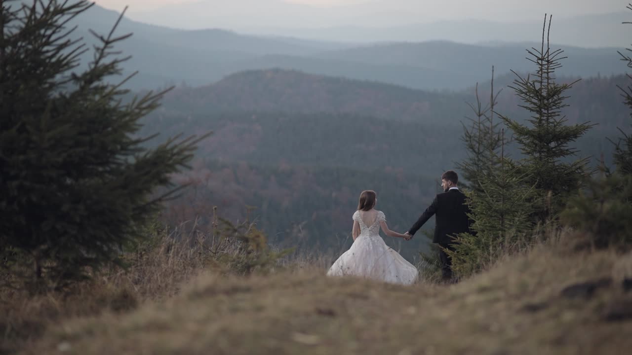 los recién casados. el novio y la novia se alejan por la ladera de la montaña. la pareja de bodas
