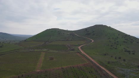 Aerial-view-following-road-going-towards-Mount-Shifon-over-landscape,-Israel