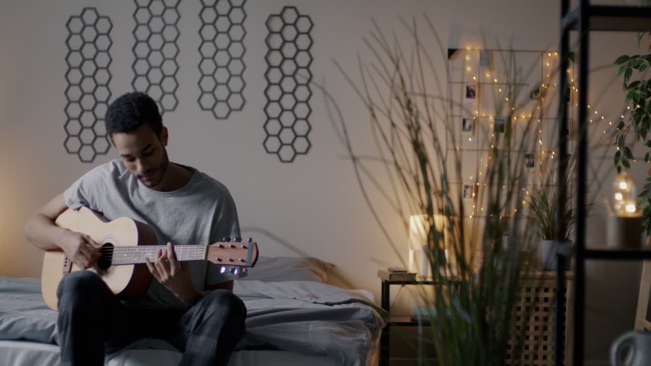 Man Playing Guitar in His Bedroom