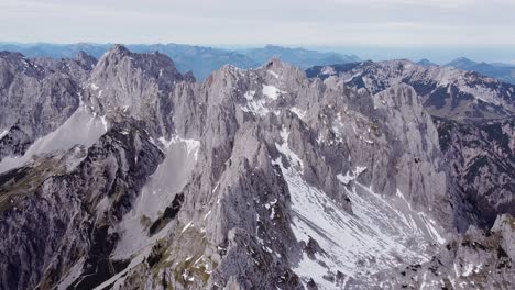 Aerial-of-steep-rocky-alpine-mountain-top-peaks,-epic-landscape-drone-scenery-view-flying-back