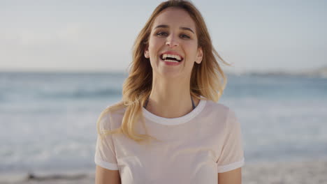 close-up-porträt einer hübschen blonden frau, die an einem spielerischen sonnigen tag am strand lacht