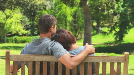 una joven pareja amorosa sentada en un banco