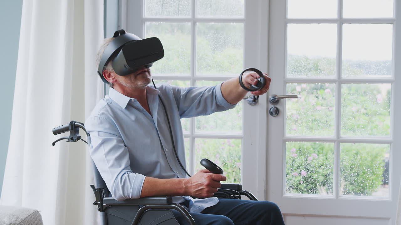 Anziano disabile in sedia a rotelle a casa che indossa un visore per la realtà virtuale e tiene in mano controller di gioco.