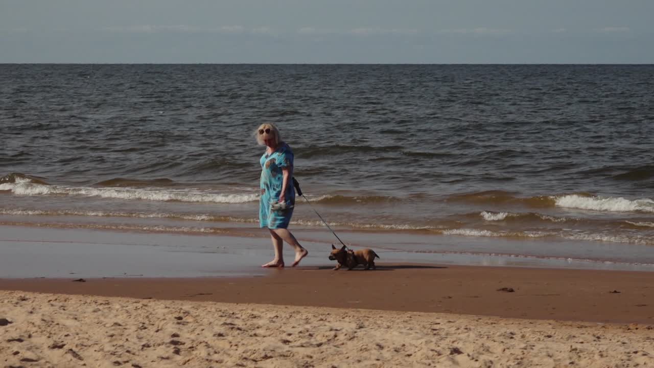 A serene beach scene where people rest by the sea, walking along the shoreline and swimming in the calm waters. The relaxed atmosphere captures a peaceful day at the coast with activities in the sun.