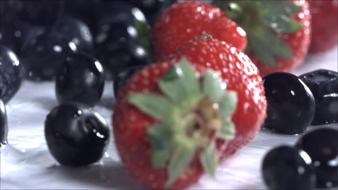 블루베리와 딸기가  바탕에 굴러 내려오고 있습니다. 느린 동작