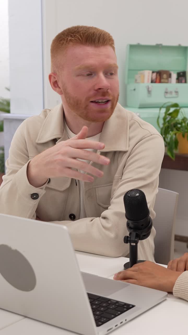 Uomo dai capelli rossi che parla e gesticola durante un'intervista per un podcast
