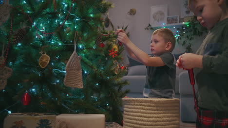 Two-boys-decorate-Christmas-tree-christmas-tree-in-the-living-room-with-Christmas-toys.-Preparing-for-the-new-year-and-Christmas.-High-quality-4k-footage